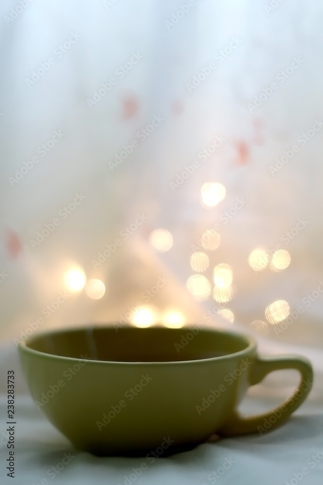 Cup of hot tea. Book and fairy lights in the background. Seletive focus. Cup of hot tea. Book and fairy lights in the background. Seletive focus.