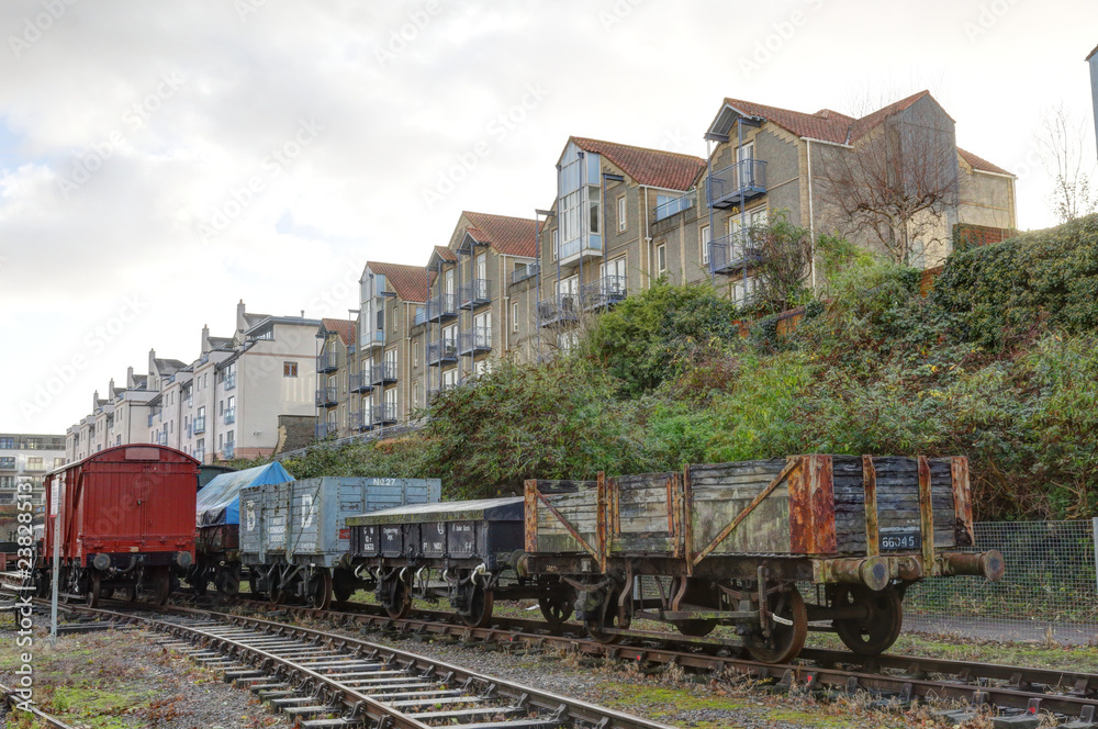 Industrial train coaches on rails in front of terrace houses during a cloudy winter day in Spike Island, Bristol, United Kingdom