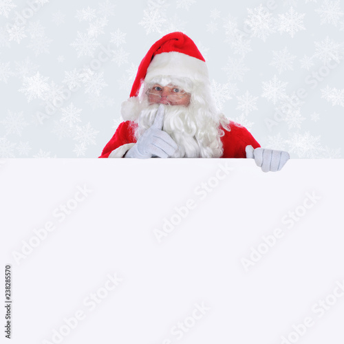 Santa Claus with blank sign making shhh sign  with a light silver background with snow flakes © Steve Cukrov