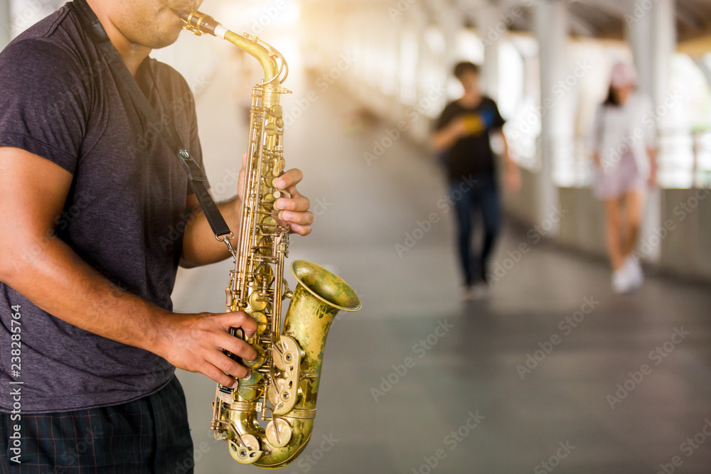 Obraz premium A street musician plays the saxophone with blurry people