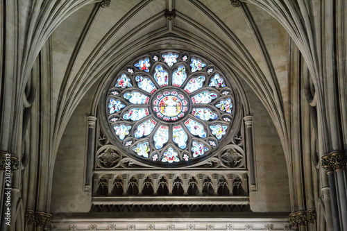 The main rose window under the pointed arch vault with colored stained glasses and Gothic decorations in the Bristol Cathedral, United Kingdom
