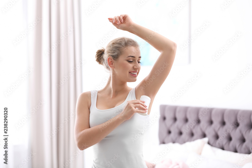 Beautiful young woman applying deodorant in bedroom Beautiful young woman applying deodorant in bedroom