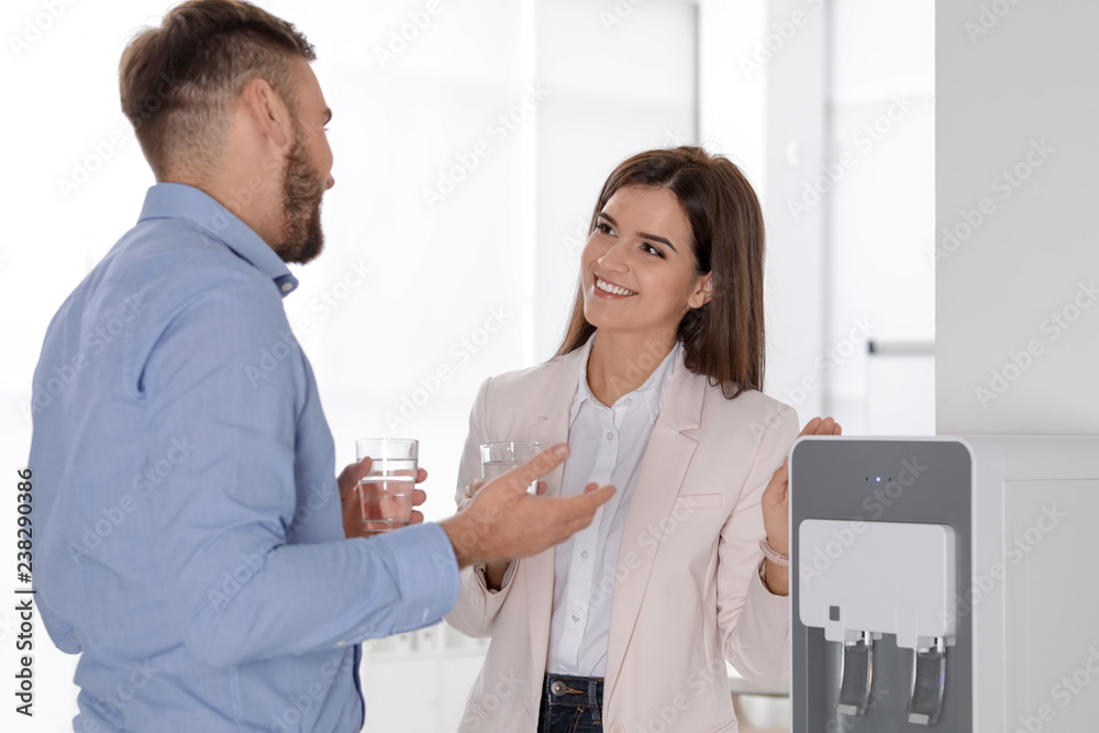 Obraz premium Employees having break near water cooler in office