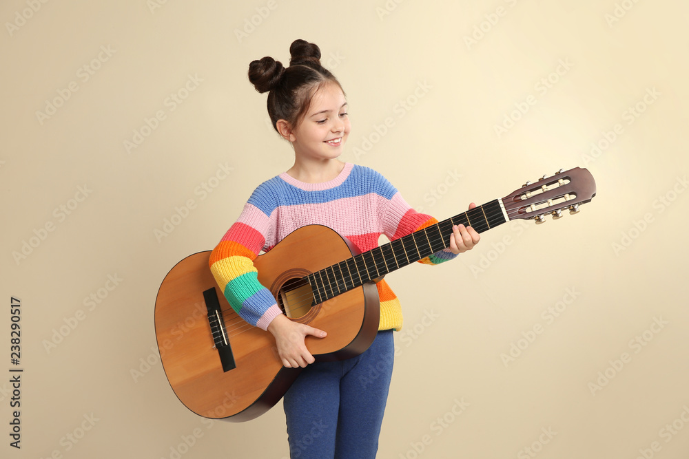 Obraz premium Cute little girl playing guitar on color background