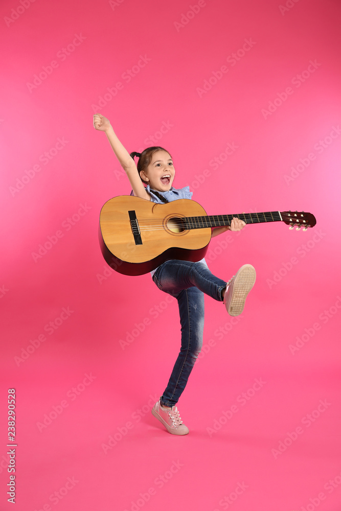 Obraz premium Cute little girl playing guitar on color background