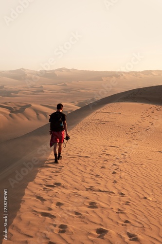 man walking on desert dune