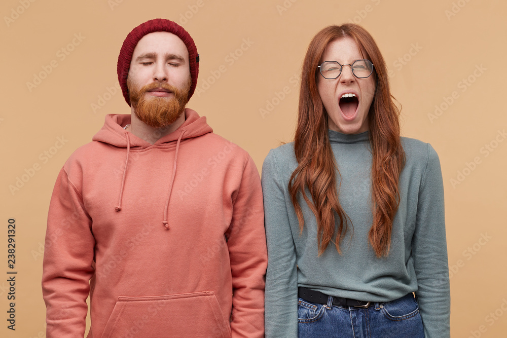 Indoor shot of young ginger beard male keeps his eye close and keep calm. Young redhead woman open mouth wide and screams, feels andgry and mad about some problems Indoor shot of young ginger beard male keeps his eye close and keep calm. Young redhead woman open mouth wide and screams, feels andgry and mad about some problems