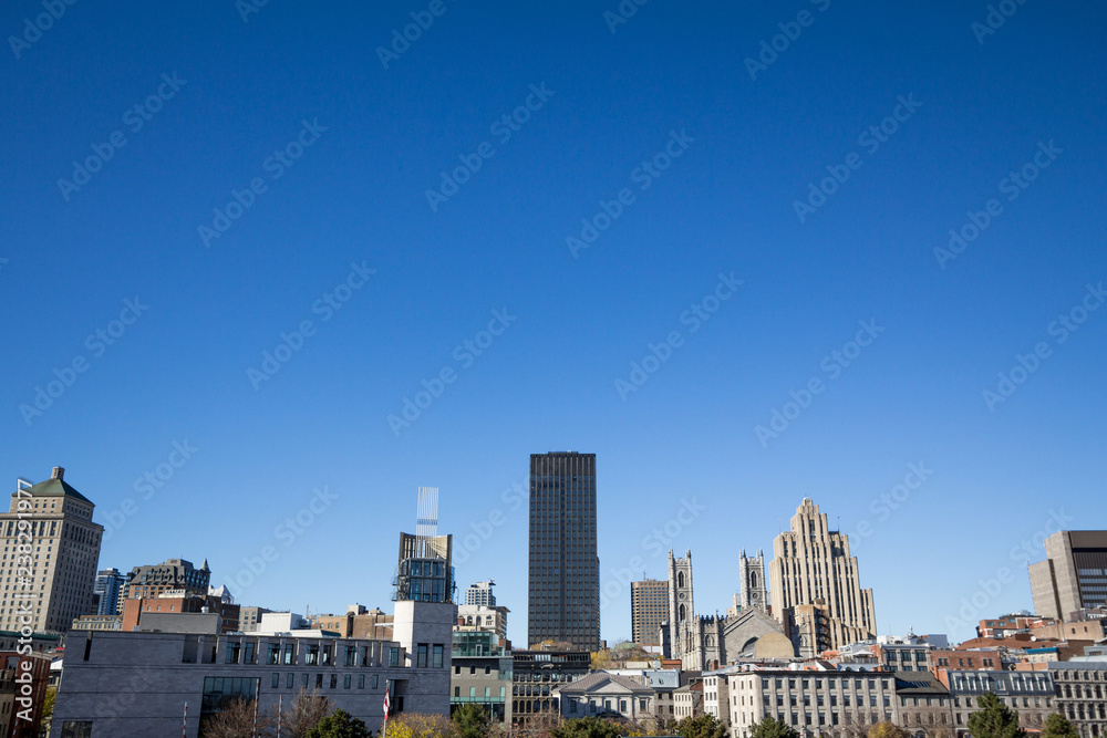 Skyline of the Old Montreal, with Notre Dame Basilica in front, and stone and glass Skyscrapers in the background. The basilica is the main cathedral of Montreal, Quebec, and a touristic landmark