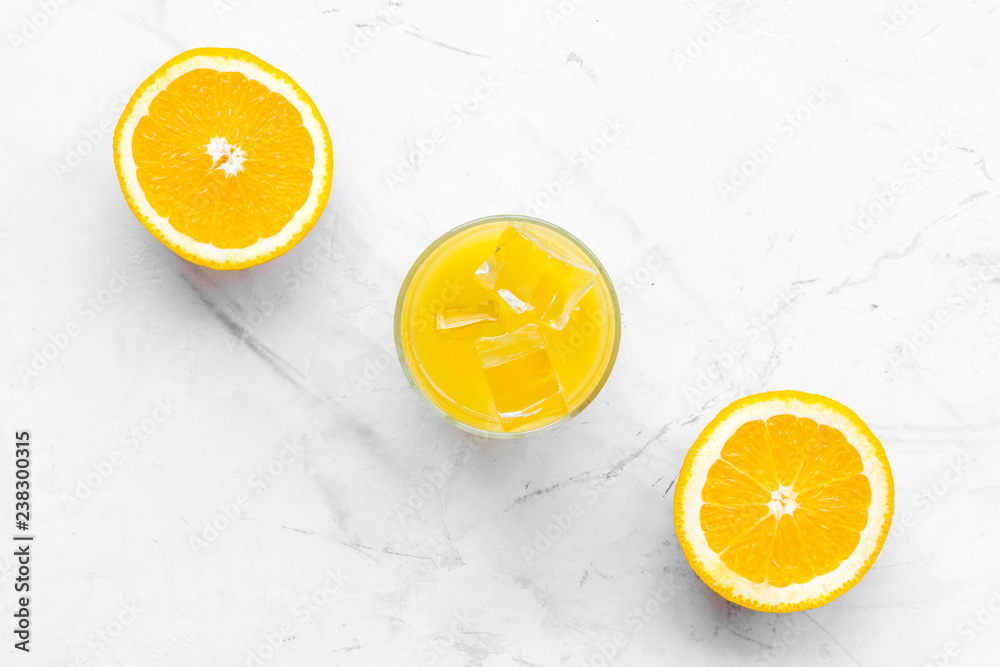 Fresh squeezed orange juice in glass near half cut oranges on white stone background top view pattern copy space