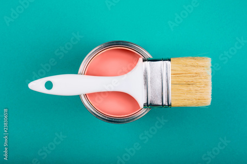 Fototapeta Naklejka Na Ścianę i Meble -  Brush on open can of Living Coral paint on blue pastel background