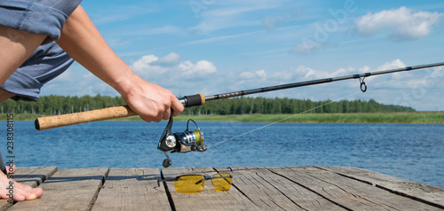 a man on the pier, holding a spinning rod for fishing, close-up