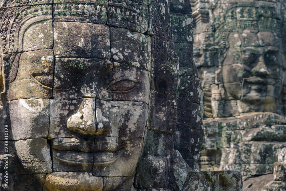 Stone faces in Angkor Thom temple, selective focus. Buddhism meditation concept, world famous travel destination, Cambodia tourism.