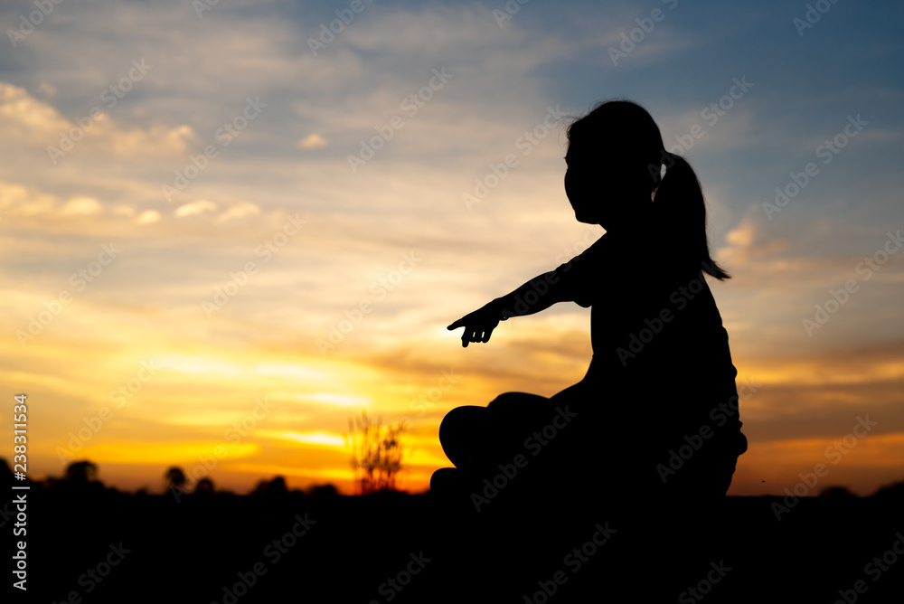 Silhouette of sad and depressed women sitting and pointing at walkway of park with sunset