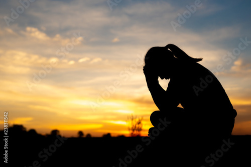 Silhouette of sad and depressed women sitting at walkway of park with sunset