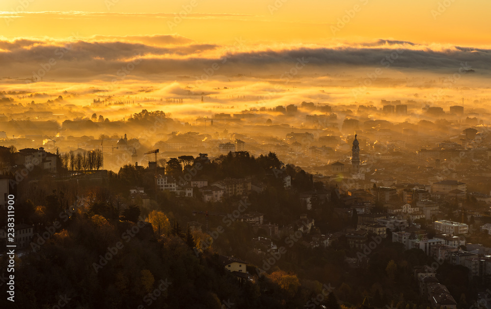 Bergamo, Italy. Amazing landscape of the town covered by the fog arising from the plain in fall season