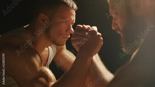 Two strong muscular men engaged in armwrestling photo