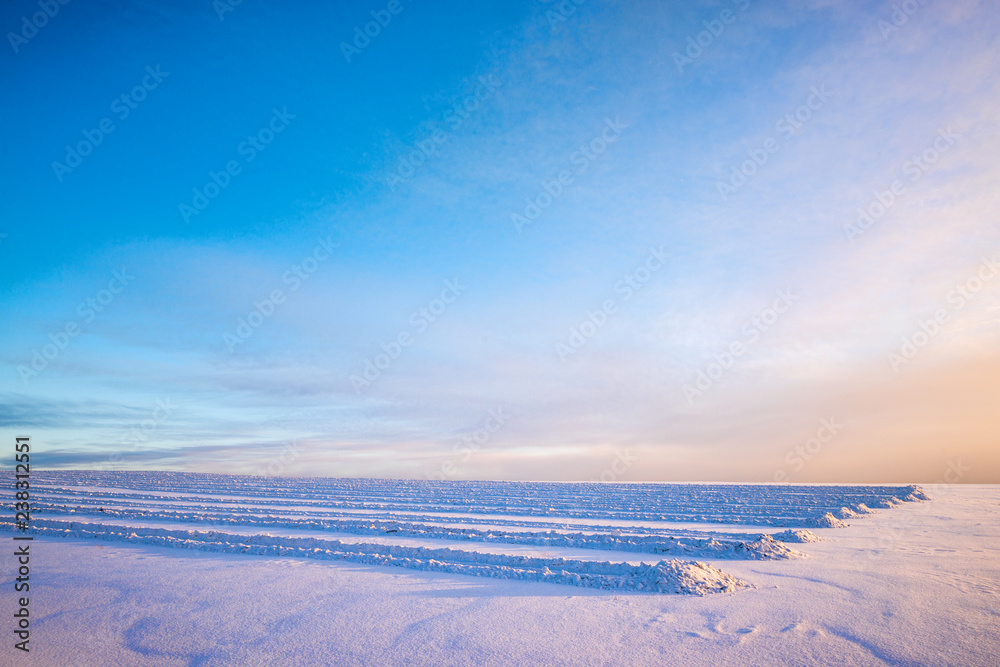 tire tracks on snow-covered field with winter blue sky on background tire tracks on snow-covered field with winter blue sky on background