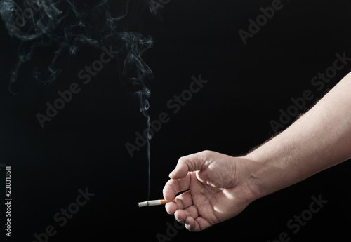 male hand with cigarette on black background