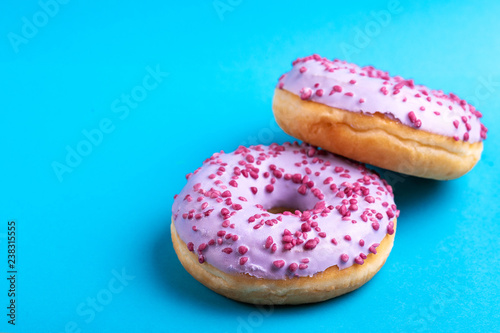 Two delicious lilac donuts with sprinkle on bright blue background