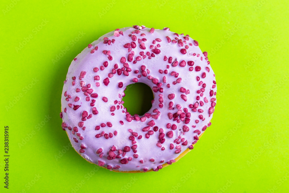 Delicious lilac donut with sprinkle on bright green background Delicious lilac donut with sprinkle on bright green background