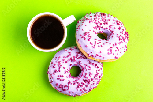 Two delicious lilac donuts with sprinkle and cup of coffee