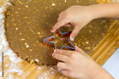 Obraz na płótnie A kid Making Star Oat Christmas Cookies in the kitchen before christmas for Sant
