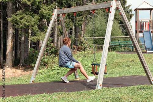 girl riding on a swing in a playground.