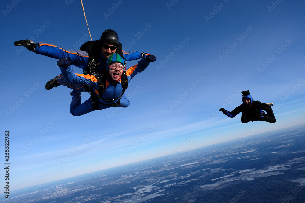 Tandem skydiving with happy girl. A cameraman is flying near tandem.