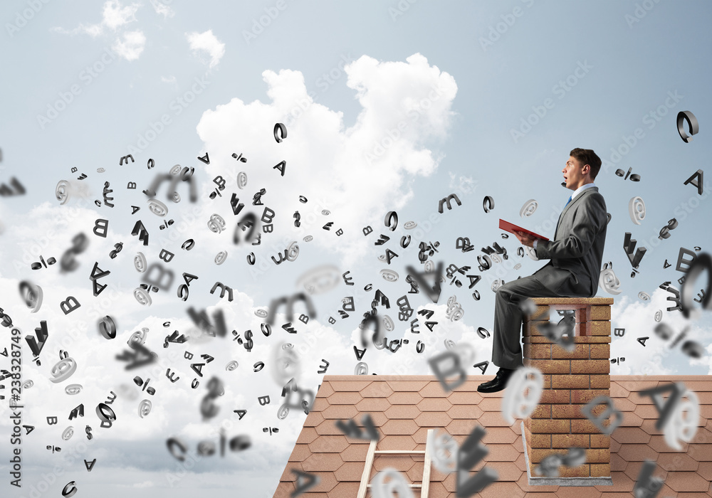 Man on brick roof reading book and symbols flying around Man on brick roof reading book and symbols flying around