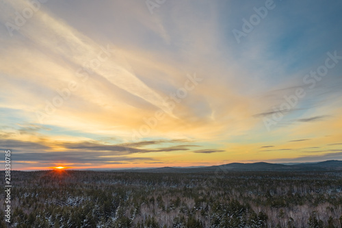 Aeria  drone panoramic view of early winter sunset  mixed forest of birches and pine trees  mountains on the background  colored dramatic sky with beautiful clouds  South Ural  Russia