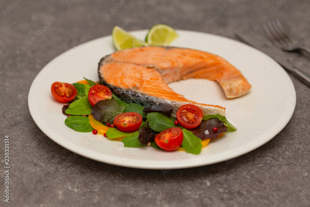 Salmon steak dinner with herbs and tomatoes.