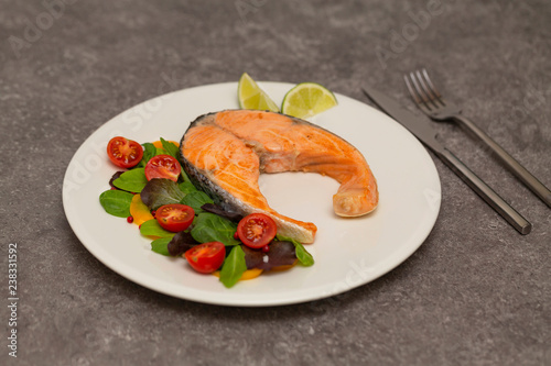 Salmon steak dinner with herbs and tomatoes.