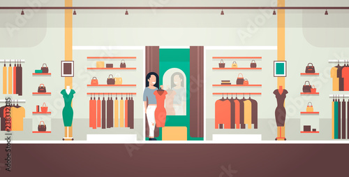 business woman trying on new dress elegant woman looking at mirror fashion shop female clothes market modern shopping mall interior flat horizontal