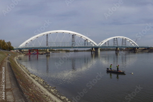 New bridge over Danube in Novi Sad, two fishermenin the boat on the river © snowyns