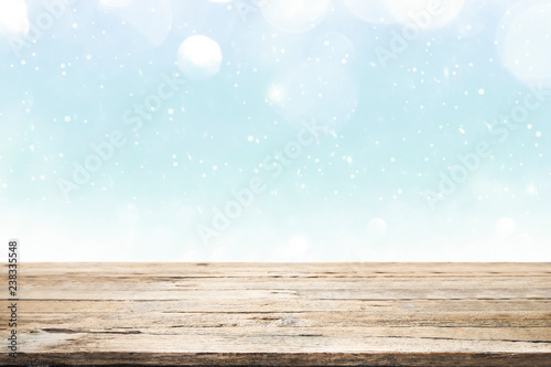 Wooden table on winter snow and white bokeh abstract.