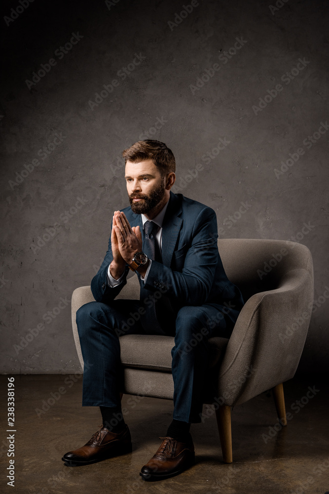 handsome businessman sitting in armchair with praying hands handsome businessman sitting in armchair with praying hands