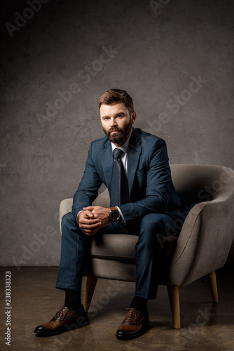 handsome bearded businessman sitting in armchair