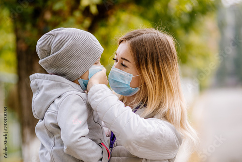 Plakat dziewczyna z dzieckiem stoi w drodze w ochronnej masce medycznej. Gęsty smog na ulicach. Epidemia grypy