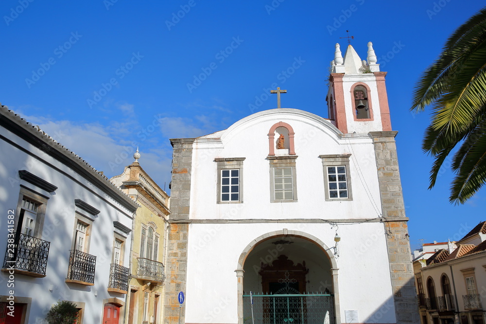 The church Nossa Senhora da Ajuda ou de Sao Paulo, located on Antonio Padinha Square, with historical buildings in the foreground, Tavira, Algarve, Portugal