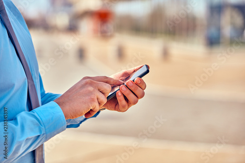 Businessman using his smartphone on the street.