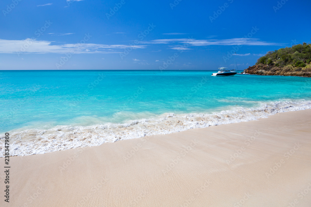 Tropical beach at Antigua island in Caribbean with white sand, turquoise ocean water and blue sky