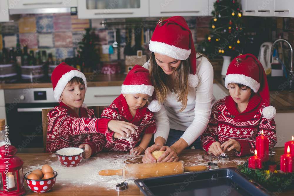 Sweet toddler child and his older brother, boys, helping mommy preparing Christmas cookies at home . Sweet toddler child and his older brother, boys, helping mommy preparing Christmas cookies at home .