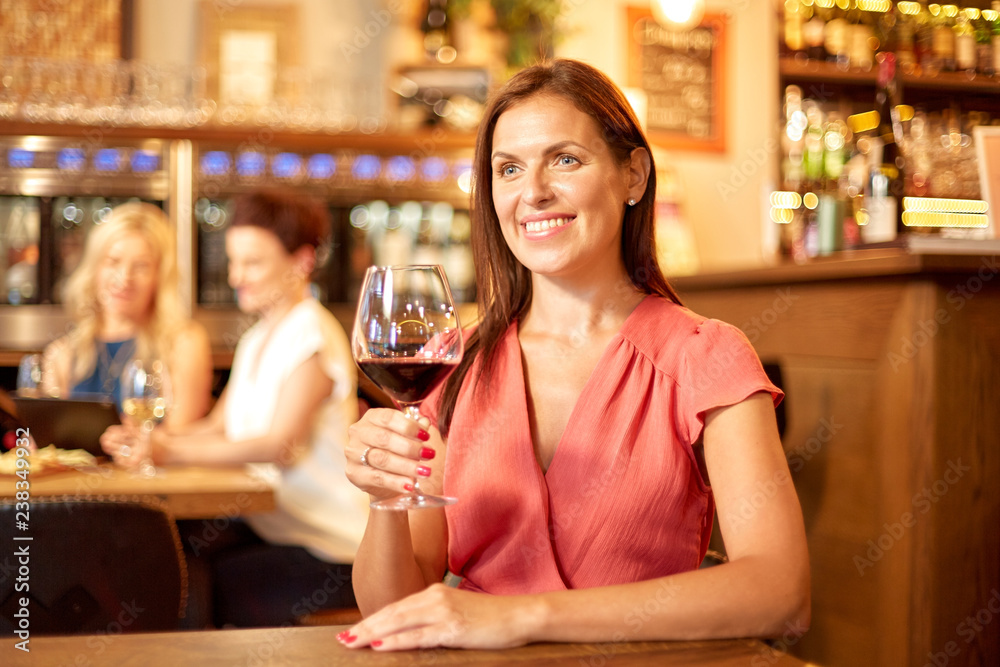 people, alcohol and lifestyle concept - happy woman drinking red wine at restaurant or bar
