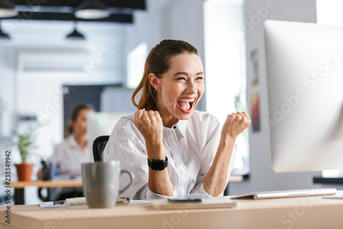 Happy young businesswoman sitting at her workplace photo