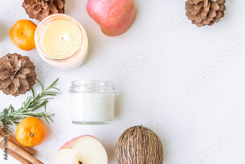 Candle, pine, apple, cinnamon on the white table. Space for text