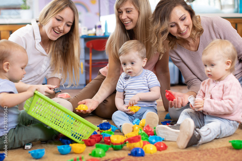 Three woman friends with babies toddlers playing on the floor in sitting room