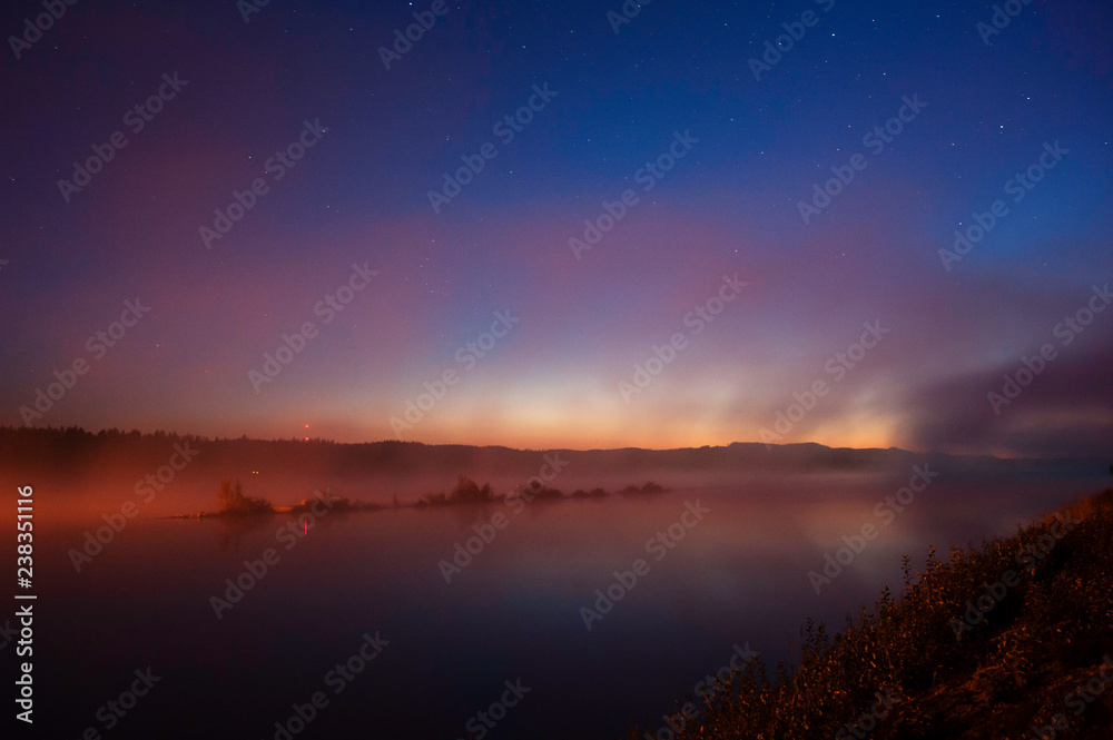 Mist over river in autumn. Darkening sky with stars after sunset.