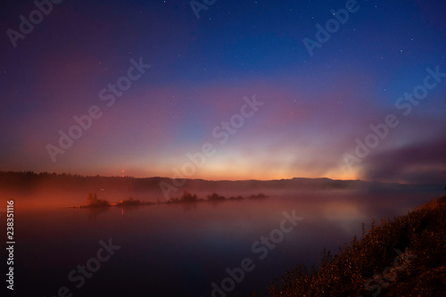 Mist over river in autumn. Darkening sky with stars after sunset.