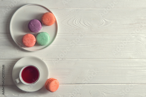 Top view. Close up. Provence breakfast. Bright macarons on a round plate, a cup of berry tea, a rustic white background. Copy space.