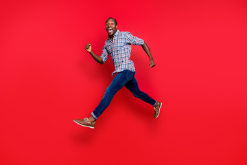 Full length body size profile side view of nice funny handsome cheerful positive sportive guy wearing checkered shirt running in air isolated on bright vivid shine red background
